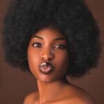 A captivating studio portrait of a young woman with an afro hairstyle, showcasing elegance and style.